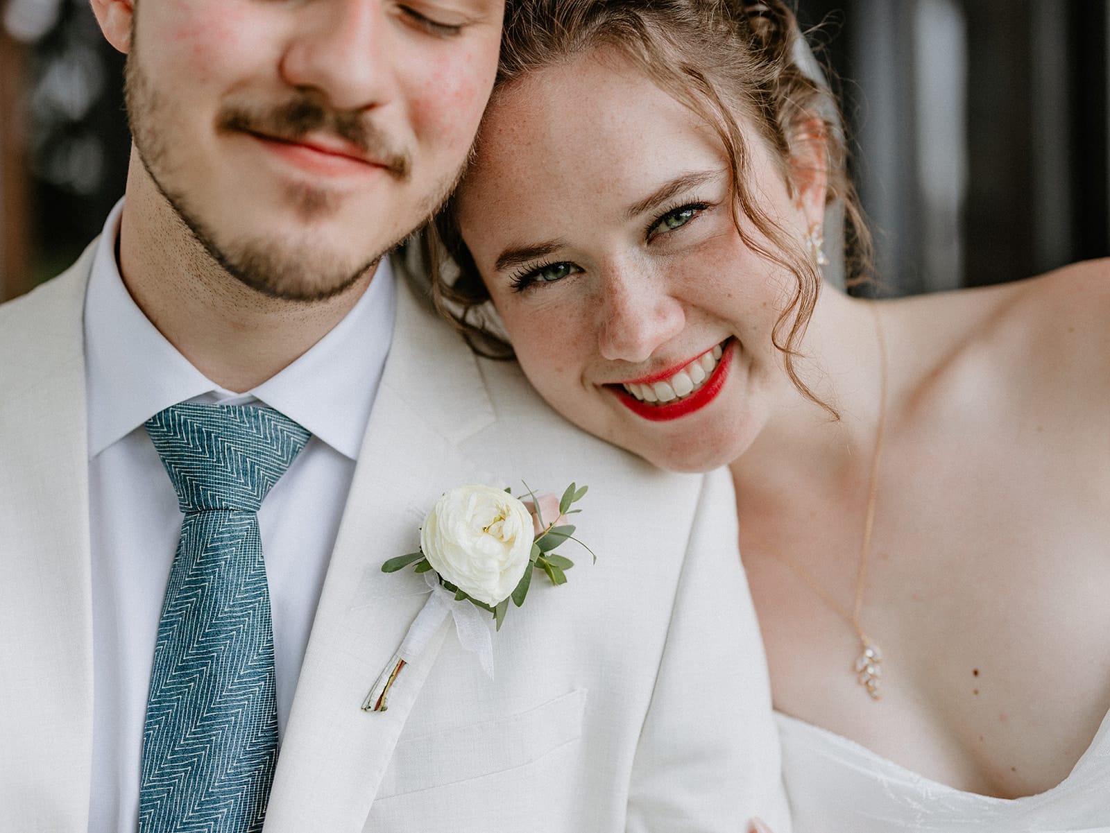 Close-up portrait of happy bride Ellsie smiling and leaning on groom Enrico at their Genesis Ranch wedding in Minnesota.