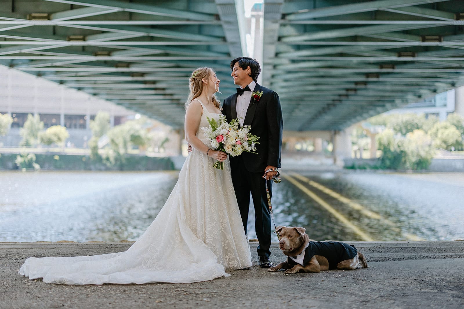 Nicollet Island Pavilion wedding photo of the bride, groom, and their dog ring bearer in a black tuxedo.